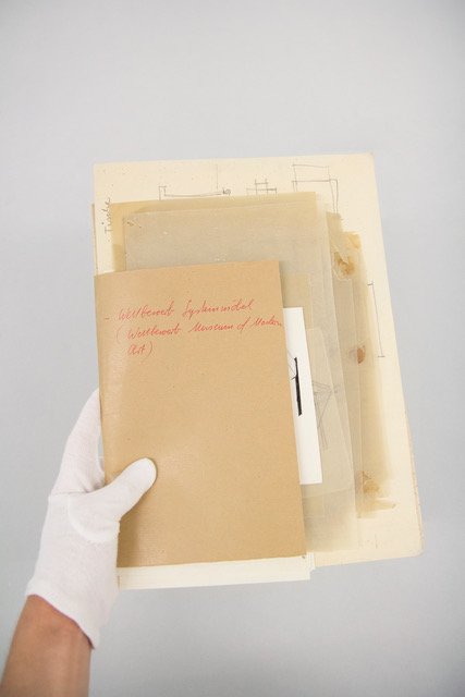 Photo of a hand holding up a folder wird various documents